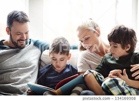 Family, reading book together with parents and kids, happiness at home with story time and learning. Love, relationship and happy people bonding in living room, education and mom, dad with children 134169308