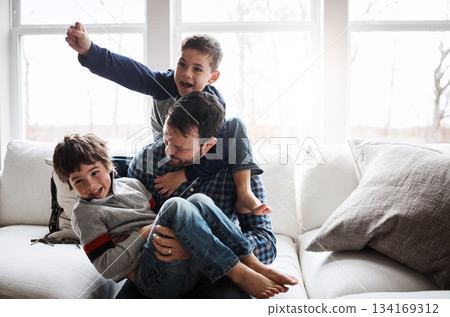 Dad with boy children, playing and energy with fun, carefree with love and laughter at family home. Man play with kids laughing in living room, crazy and playful with piggyback, hug and excited Dad with boy children, playing and energy with fun, carefree with love and laughter at family home. Man play with kids laughing in living room, crazy and playful with piggyback, hug and excited 134169312