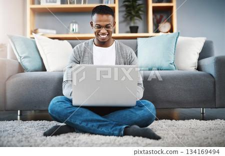 Laptop, floor and happy man with work from home, online research and typing in living room for career opportunity. Relax, carpet and young african person working on computer or technology in lounge Laptop, floor and happy man with work from home, online research and typing in living room for career opportunity. Relax, carpet and young african person working on computer or technology in lounge 134169494