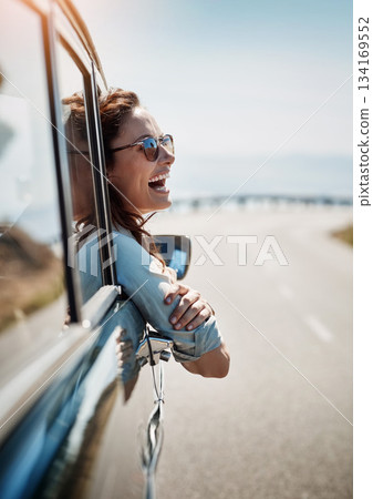 Happy, freedom and road trip with a woman in a car, looking at the view from the window while on the open road. Smile, travel and fun with a young female traveler on a journey during her vacation 134169552