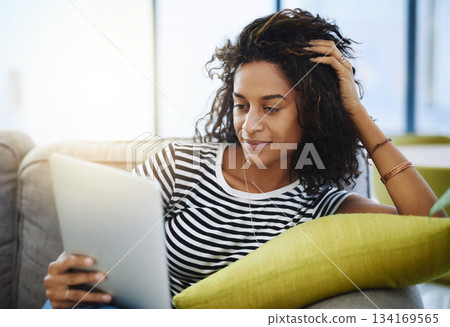 Relax, tablet and woman on sofa in home for network, online website and social media. Communication, mobile app and African female person on digital tech for streaming, videos and internet connection 134169565