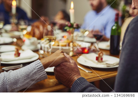 Prayer, thanksgiving and hand holding with family at table in dining room for holiday, food or worship. Praying, support and gratitude with closeup of people at home for kindness, dinner and love 134169698