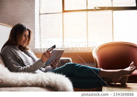 Relax, tablet and credit card with a woman banking online on a sofa in the living room of her home. Ecommerce, financial freedom and shopping with a young female customer or consumer in her house Relax, tablet and credit card with a woman banking online on a sofa in the living room of her home. Ecommerce, financial freedom and shopping with a young female customer or consumer in her house 134169886
