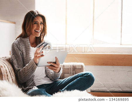 Idea, tablet and credit card with a woman online shopping while sitting on a sofa in the living room at home. Ecommerce, finance and online banking with a young female customer thinking in her house 134169895
