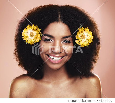 Portrait of happy woman, afro and yellow flowers in studio background for beauty, floral aesthetic and shine. Face of african model, skincare and daisy plants in hair for happiness, perfume or makeup 134170009