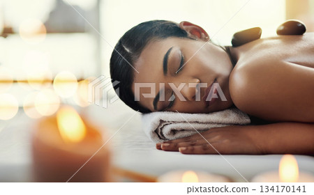 Woman, relax and sleeping on bed at spa for rock massage, skincare or beauty body treatment at resort. Calm female asleep with eyes closed and hot rocks on back in healthy physical therapy at salon 134170141