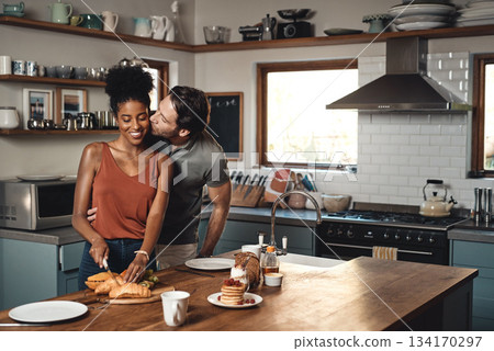 Interracial couple, kiss and cooking breakfast in kitchen for morning, love or care in marriage at home. Happy man kissing woman for food, nutrition or hug in happiness for healthy relationship 134170297
