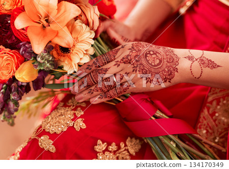 Henna, hands and Indian woman at her wedding event with flowers or bouquet for decoration or design. Luxury, marriage and traditional culture by a bride with art pattern on her hand for celebration 134170349