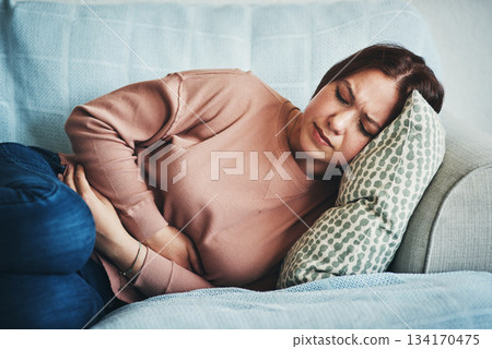 Stomach ache, pain and woman on home sofa with menstrual or period cramps in lounge. Sick, abdomen or colon problem of a female person with hands on tummy for constipation, digestion or virus Stomach ache, pain and woman on home sofa with menstrual or period cramps in lounge. Sick, abdomen or colon problem of a female person with hands on tummy for constipation, digestion or virus 134170475
