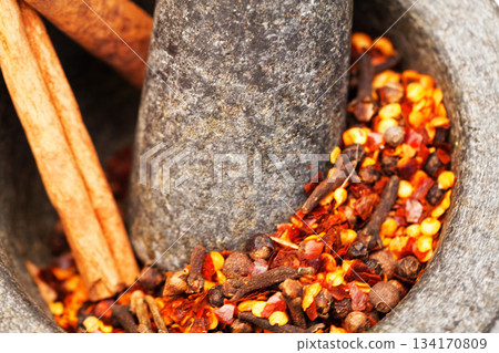 Closeup, herbs and crush spices for curry on stone mortar or bowl or grind for powder seasoning and on close up. Nutrition, diet and garlic or pestle in coriander or natural salt for taste in food 134170809