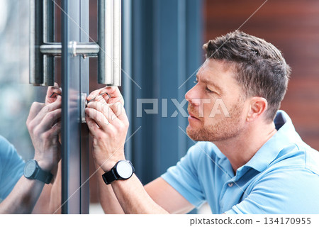 Door, locksmith and man at a house for home renovation, repair and diy lock, change or installation. Safety, maintenance and male handyman person checking keyhole for security or entrance inspection 134170955