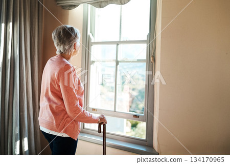 Senior woman, nursing home and window for thinking, vision or ideas with walking stick, disability or rehabilitation. Elderly lady, remember or looking ahead in retirement, house or memory in morning 134170965