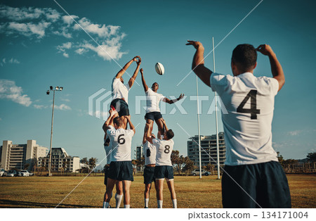 Team, rugby and jump or lift, ball and teamwork or sport, training for game and fitness, exercise or sports performance with blue sky. Group, men and lifting man to catch and professional match 134171004