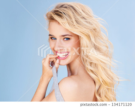 Portrait, hair and smile with a woman on a blue background in studio for shampoo treatment at a salon. Face, happy and haircare with an attractive young female model posing for natural beauty 134171120
