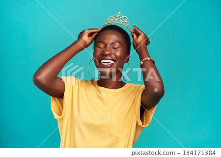 Crown, happy and excited princess or black woman with happiness isolated in a blue background studio. Celebration, winner and young female person celebrating with a tiara for an achievement or prom Crown, happy and excited princess or black woman with happiness isolated in a blue background studio. Celebration, winner and young female person celebrating with a tiara for an achievement or prom 134171384