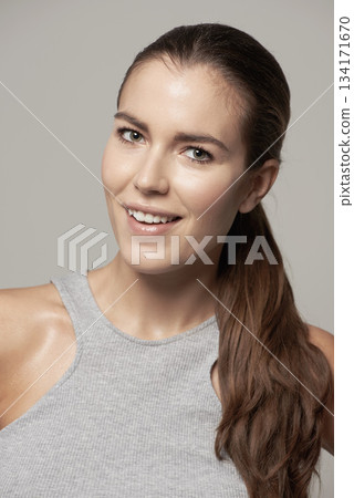 Happy woman, portrait and smile for fitness, exercise or cardio workout against a grey studio background. Face of fit, active and sweaty female person or model smiling in sportswear or exercising 134171670