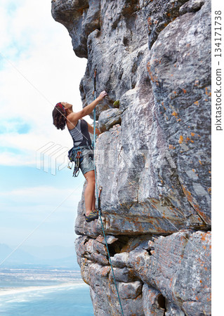 Rock climbing, blue sky and challenge with woman on mountain for adventure, travel and explore. Strong, freedom and cliff with female climber training in nature for courage, safety and workout Rock climbing, blue sky and challenge with woman on mountain for adventure, travel and explore. Strong, freedom and cliff with female climber training in nature for courage, safety and workout 134171738