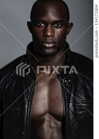 Fashion, portrait and black man in leather jacket in studio isolated on a gray background. African male model, serious face and coat, confidence and stylish clothes or trendy outfit from Nigeria. 134171804