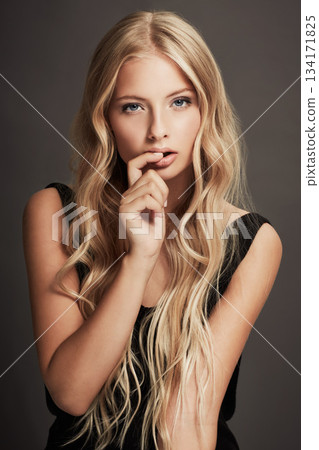 Beauty, face and portrait of a seductive woman with makeup, cosmetics and long hair in studio. Sexy female aesthetic model with skin glow, luxury skincare and finger in mouth on a grey background 134171825