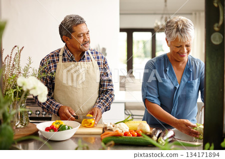 Food, elderly couple and cooking while happy in kitchen of their home. Teamwork or help, vegetables and senior married people preparing a meal for dinner or lunch together in their house. Food, elderly couple and cooking while happy in kitchen of their home. Teamwork or help, vegetables and senior married people preparing a meal for dinner or lunch together in their house. 134171894