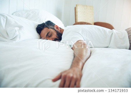 Tired, dream and a man on a bed for sleep, relax and fatigue at home. Rest, napping and a guy sleeping in the bedroom with insomnia, narcolepsy or content while lying down and dreaming in the morning 134171933