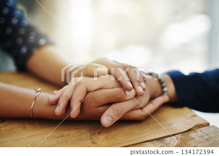Holding hands, support and closeup with trust, solidarity and community on a home table. Therapy, diversity and gratitude of friends together with hope, respect and love for grief empathy and forgive 134172394