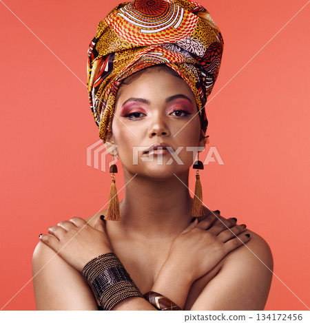 African fashion, beauty and portrait of woman on orange background with cosmetics, makeup and accessories. Glamour, model and face of female person with exotic jewelry, traditional style and scarf African fashion, beauty and portrait of woman on orange background with cosmetics, makeup and accessories. Glamour, model and face of female person with exotic jewelry, traditional style and scarf 134172456