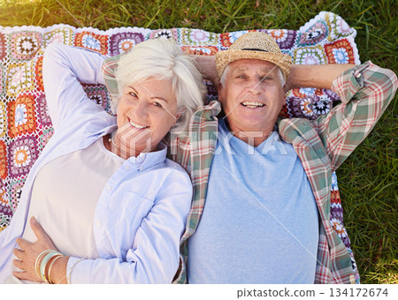 Portrait, picnic and an elderly couple lying on a blanket in a field together for romance or bonding from above. Relax, smile and retirement with happy seniors outdoor in the countryside for dating 134172674