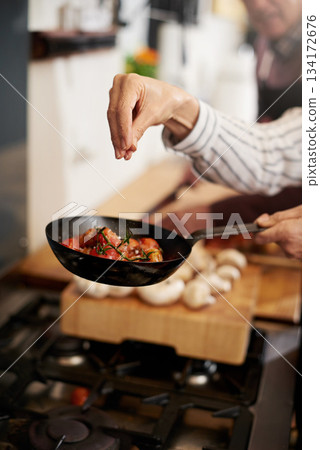 Hand, cooking and seasoning with a chef in the kitchen for meal preparation in a home for dinner. Healthy, diet and nutrition with food in a pan for wellness, hunger or satisfaction in a house 134172676