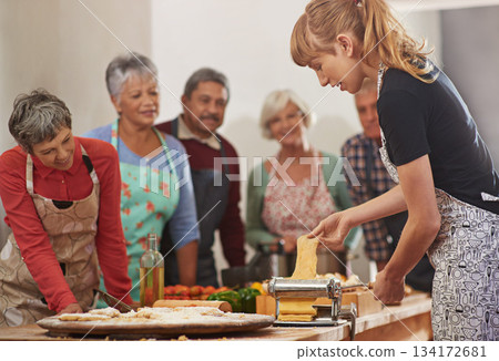 Food, senior cooking class and a woman teaching people in the kitchen of a home for meal preparation. Pasta maker, equipment and learning with mature friends watching a female chef follow a recipe 134172681