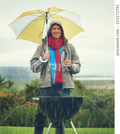 Happy man, umbrella and barbecue in rain with beer for meal, supper or dinner on the fire grill. Male person smiling for insurance, cover or protection while cooking under raining or stormy weather Happy man, umbrella and barbecue in rain with beer for meal, supper or dinner on the fire grill. Male person smiling for insurance, cover or protection while cooking under raining or stormy weather 134172791