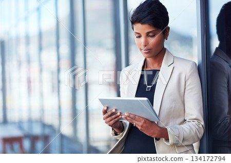 Tablet, mockup and corporate with a business woman leaning against a glass wall or window at the office. Technology, research and space with a young professional female employee working online 134172794