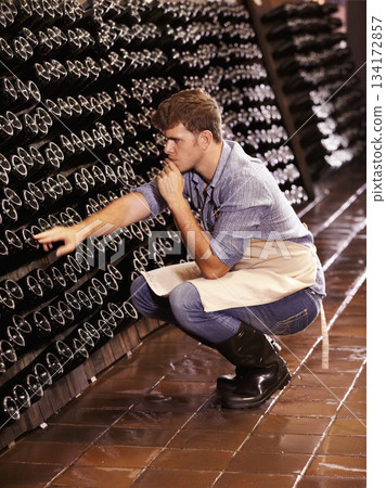 Winery, man and counting bottles of wine in cellar, warehouse or factory. Alcohol, manufacturing and male person count, inspection or quality control at production plant or distillery while thinking. 134172857