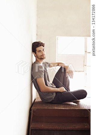Portrait, relax and stairs with a man sitting by a window on the landing of a staircase while alone in his home. Happy, content and lifestyle with a handsome young male person laid-back in a house Portrait, relax and stairs with a man sitting by a window on the landing of a staircase while alone in his home. Happy, content and lifestyle with a handsome young male person laid-back in a house 134172866