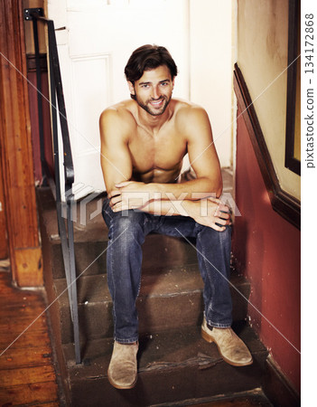 Happy portrait, shirtless and a sexy man on stairs with a smile, confidence and positive mindset. A happy male model person sitting on steps for art deco, fitness and fashion in apartment or house 134172868