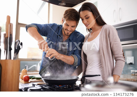 Happy couple, pan and cooking together in the kitchen with food or healthy ingredients for dinner at home. Man and woman smiling in happiness for meal preparation, lunch or frying vegetables on stove 134173276