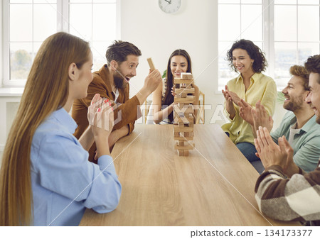 Group of happy friends sitting around table, playing game and having fun together 134173377