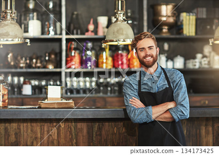 Happy, crossed arms and portrait of male barista standing by the counter in his startup cafeteria. Smile, success and young man small business owner with confidence in coffee shop or restaurant. Happy, crossed arms and portrait of male barista standing by the counter in his startup cafeteria. Smile, success and young man small business owner with confidence in coffee shop or restaurant. 134173425