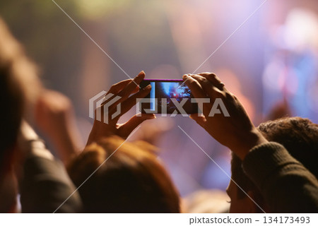 Music, concert and phone camera in the audience to record a performance on stage at a festival or event. Party, video or photograph with a person in the crowd of a stadium at night holding a mobile Music, concert and phone camera in the audience to record a performance on stage at a festival or event. Party, video or photograph with a person in the crowd of a stadium at night holding a mobile 134173493