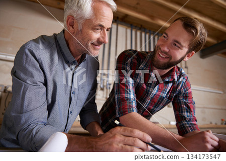 Architecture, teamwork and man with apprentice in workshop for collaboration. Senior engineer, men and smile with trainee, working on remodeling project and drawing plans on paperwork with mentor. 134173547