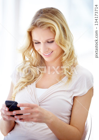 Happy woman, phone and smile for communication, social media or texting while sitting on chair at home. Female person smiling in happiness for chatting, browsing or research on mobile smartphone app 134173714