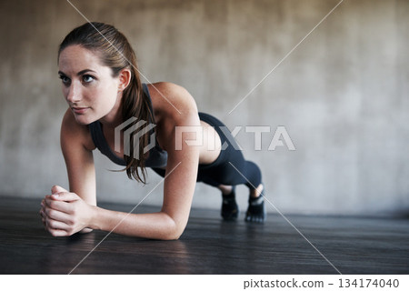 Fitness, woman and plank in workout, exercise or training strong core, abs or determination at gym. Serious, fit and confident female planking or working on abdominal muscle for healthy wellness 134174040
