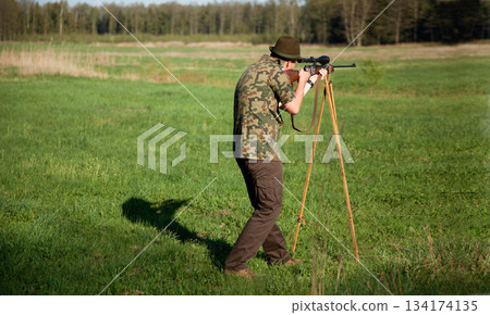Hunter, gun and man in field in nature on a Africa safari for animal shooting with a weapon on vacation. Hunting sport, male person and target hunt practice of a traveler in camouflage with a scope Hunter, gun and man in field in nature on a Africa safari for animal shooting with a weapon on vacation. Hunting sport, male person and target hunt practice of a traveler in camouflage with a scope 134174135