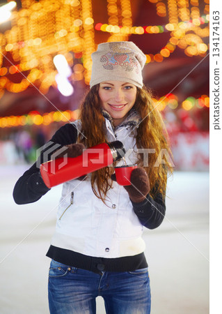 Woman, ice skating portrait and coffee thermos in night with smile, pour or happy on winter vacation. Girl, happiness or warm drink for cup of matcha, espresso or latte for energy, fitness or holiday 134174163