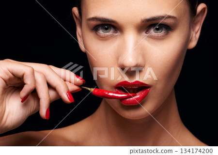 Beauty, portrait and woman with a chilli in a studio for a sensual, glamour and sexy aesthetic. Cosmetic, makeup and female model with a pepper with red lipstick isolated by a dark black background. 134174200