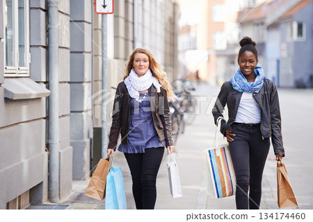 Friends, city or women walking with shopping bag for retail sales deal, discount or promotion offers. Fashion bags, diversity or happy people on urban sidewalk street together with smile or freedom 134174460
