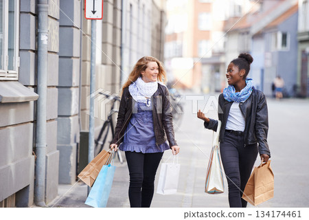 Friends, city or happy people walking with shopping bag for retail sales deal, discount or promotion offers. Fashion bags, diversity or women talking on sidewalk street together with smile or freedom 134174461