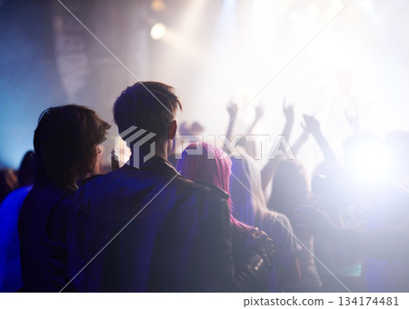 Dance, rock and friends in crowd at music festival from back, watching live band performance on stage. Audience in arena, lights and group of people at party, fans of musician at concert together. Dance, rock and friends in crowd at music festival from back, watching live band performance on stage. Audience in arena, lights and group of people at party, fans of musician at concert together. 134174481