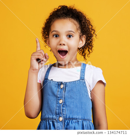 Idea, surprise and portrait of a girl pointing isolated on a yellow studio background with shock. Plan, knowledge and happy little child with bright ideas, wow and smart planning gesturing to space 134174711