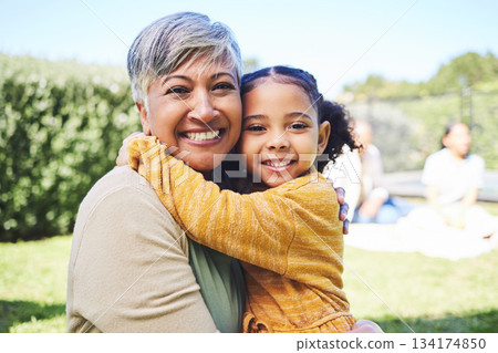 Grandmother, girl and garden portrait with hug, love and bond in summer sunshine with family. Senior woman, female child and embrace with excited face, pride and care with happiness on backyard lawn 134174850